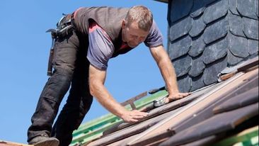 A roofer retiling a roof