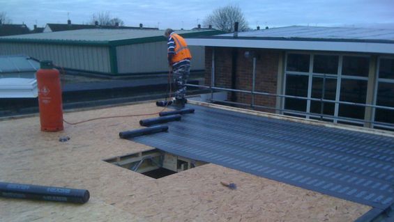 Roofing experts installing a flat roof
